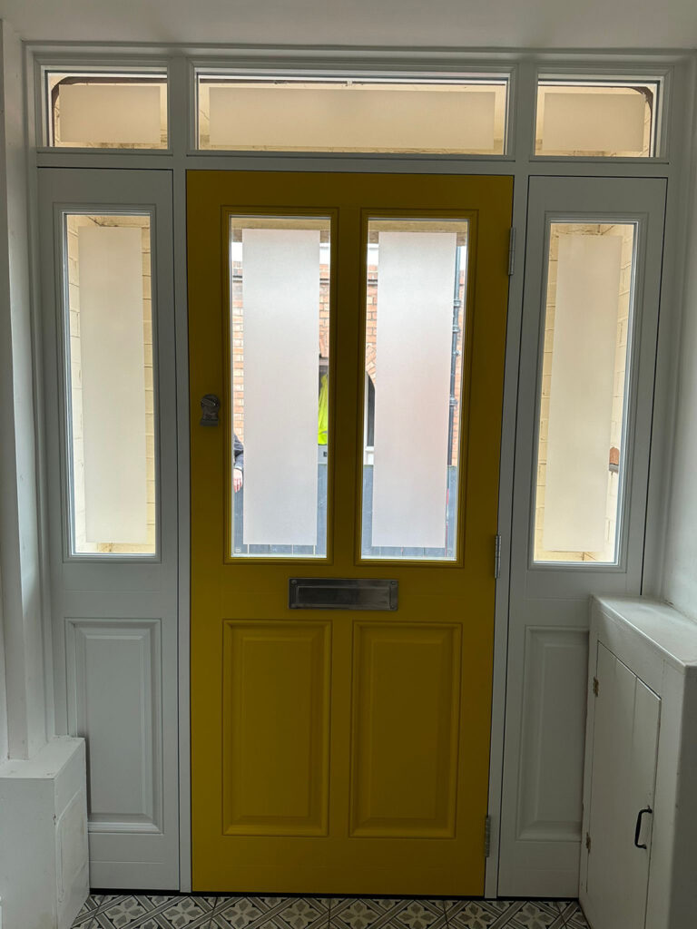 a yellow front door with white sidelights