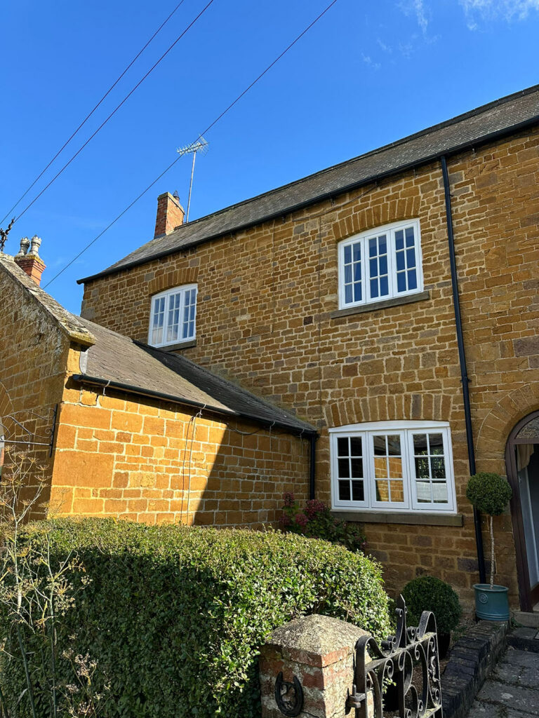 three white casement windows on a yellow brick building