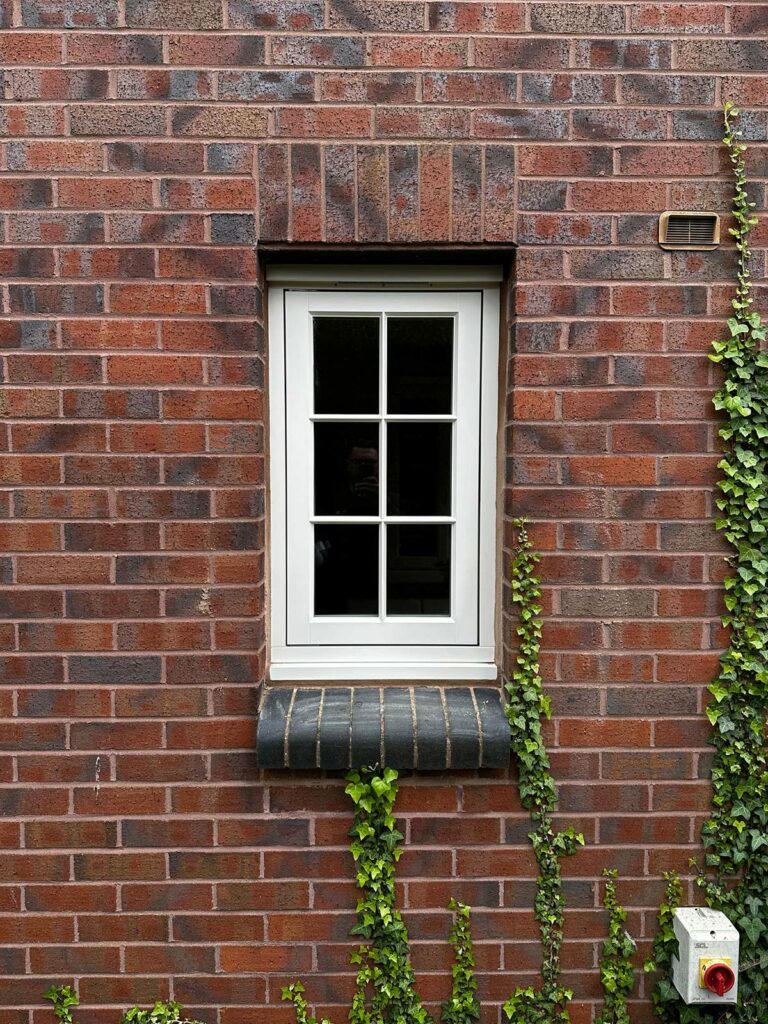 a singular flush casement window on a red brick building