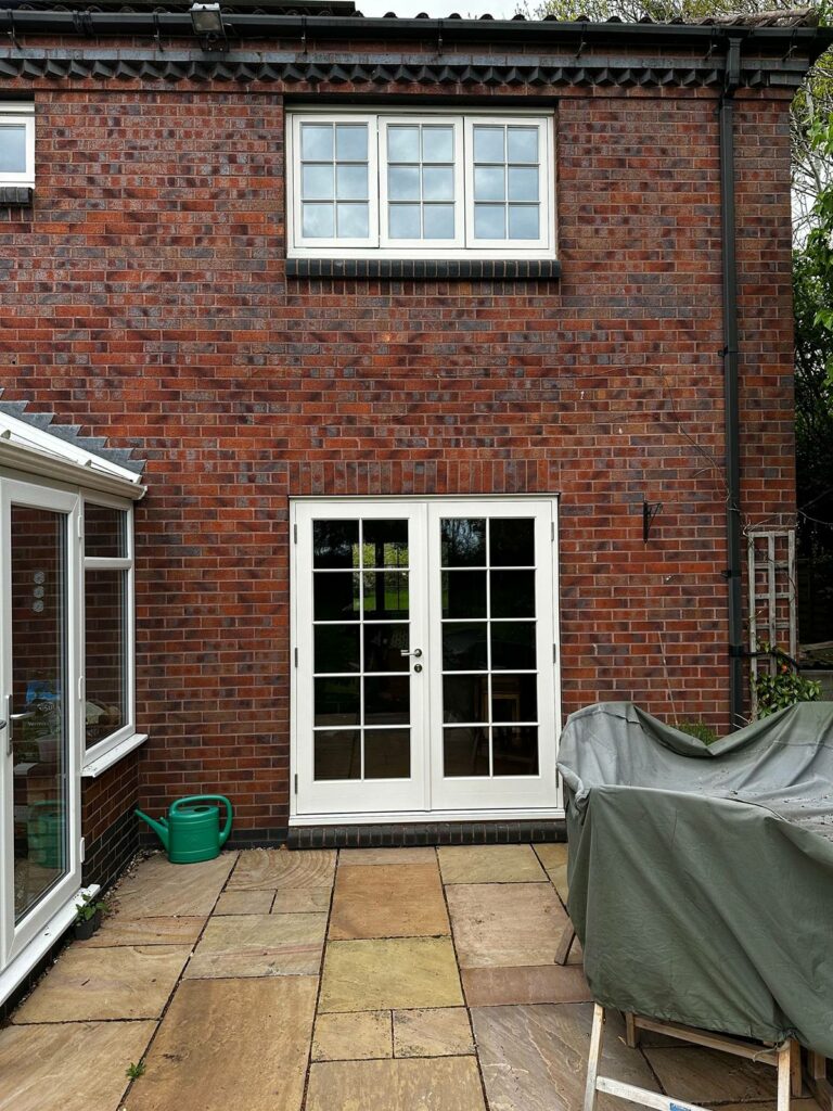 cream coloured windows and french doors on a red brick building