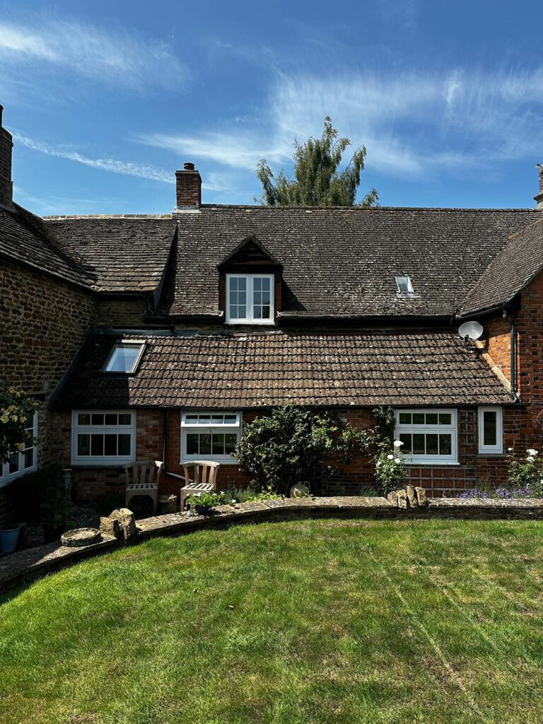 the back of a red brick home with white windows and doors