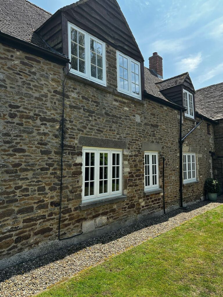 the back of a red brick home with white windows and doors