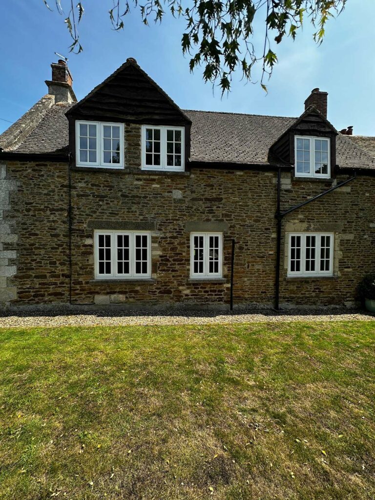 the back of a red brick home with white windows and doors