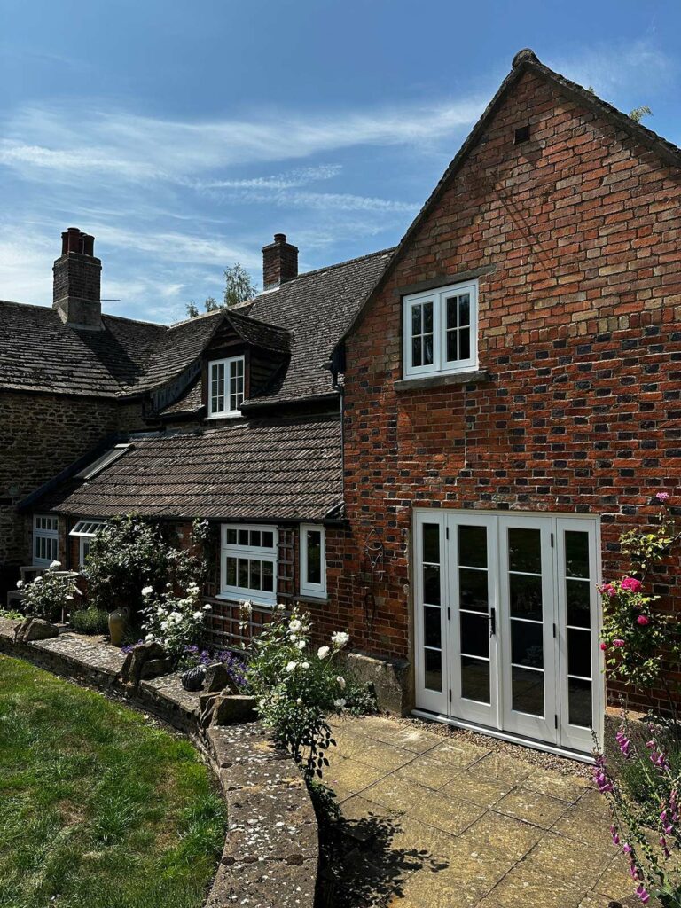 the back of a red brick home with white windows and doors