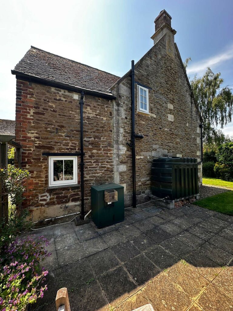 the back of a red brick home with white windows and doors