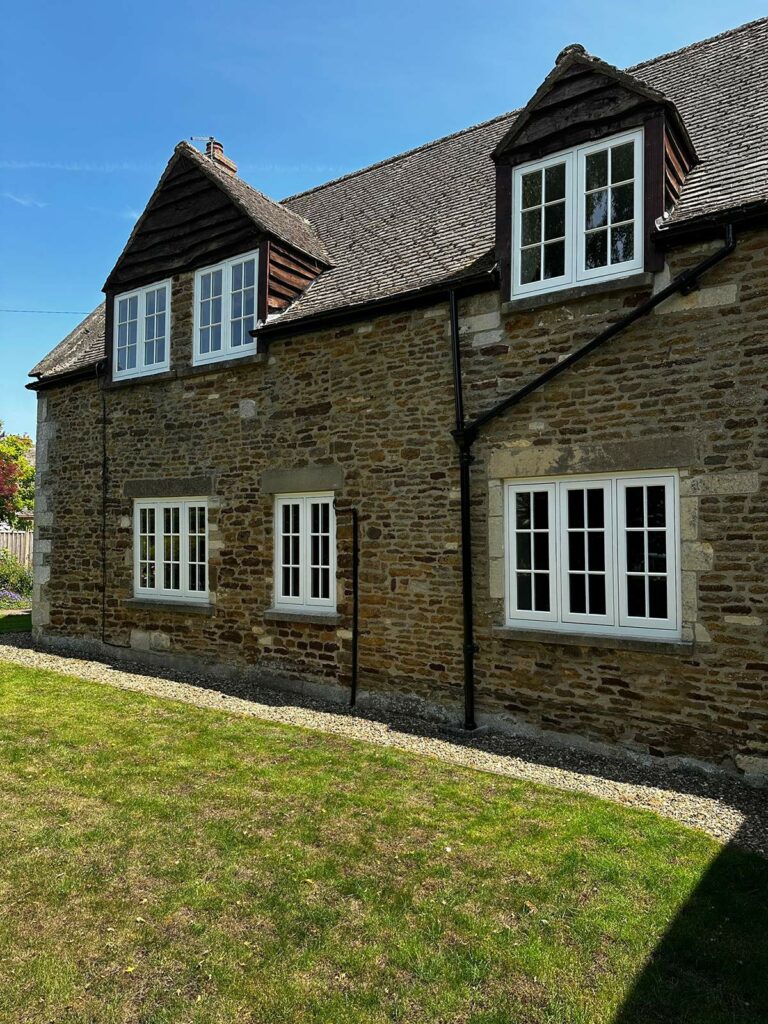 the back of a red brick home with white windows and doors