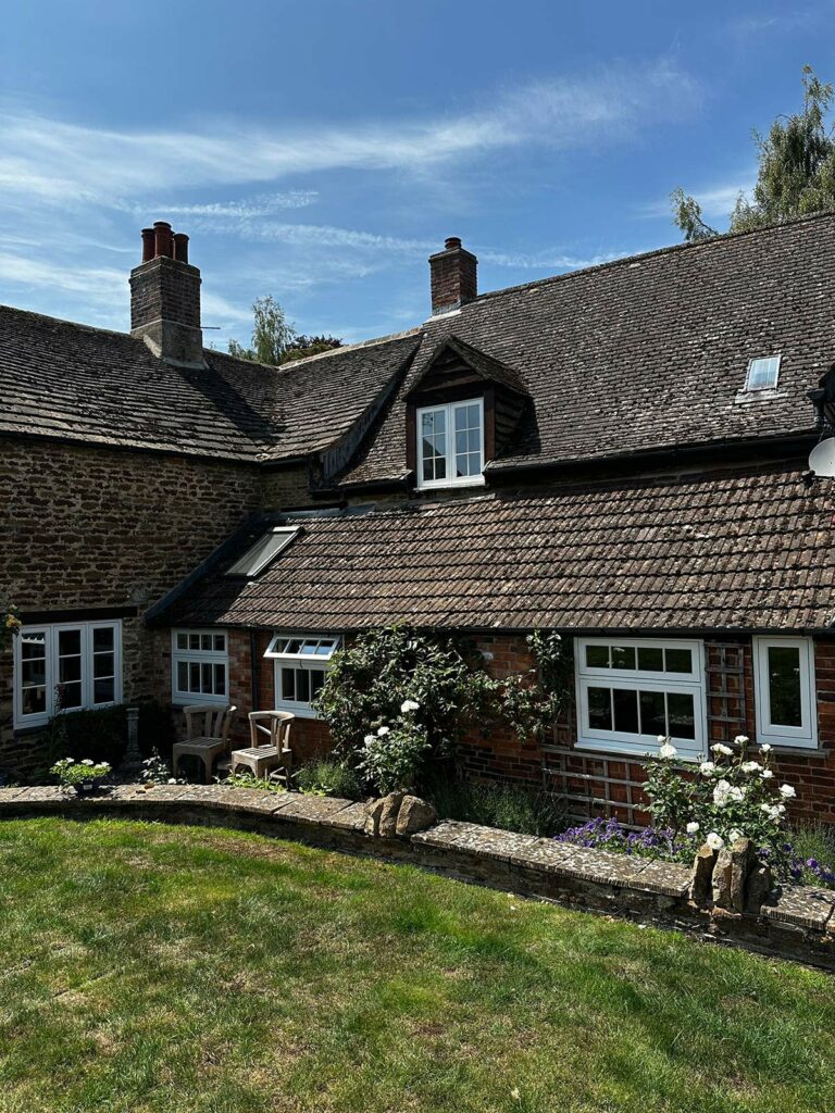 the back of a red brick home with white windows and doors