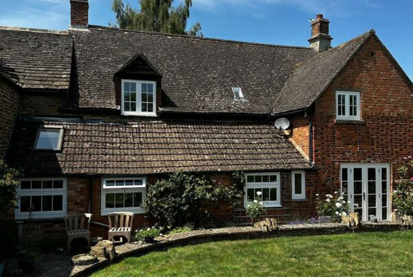 the back of a red brick home with white windows and doors