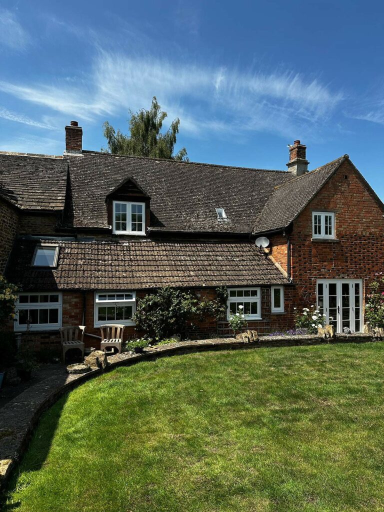 the back of a red brick home with white windows and doors