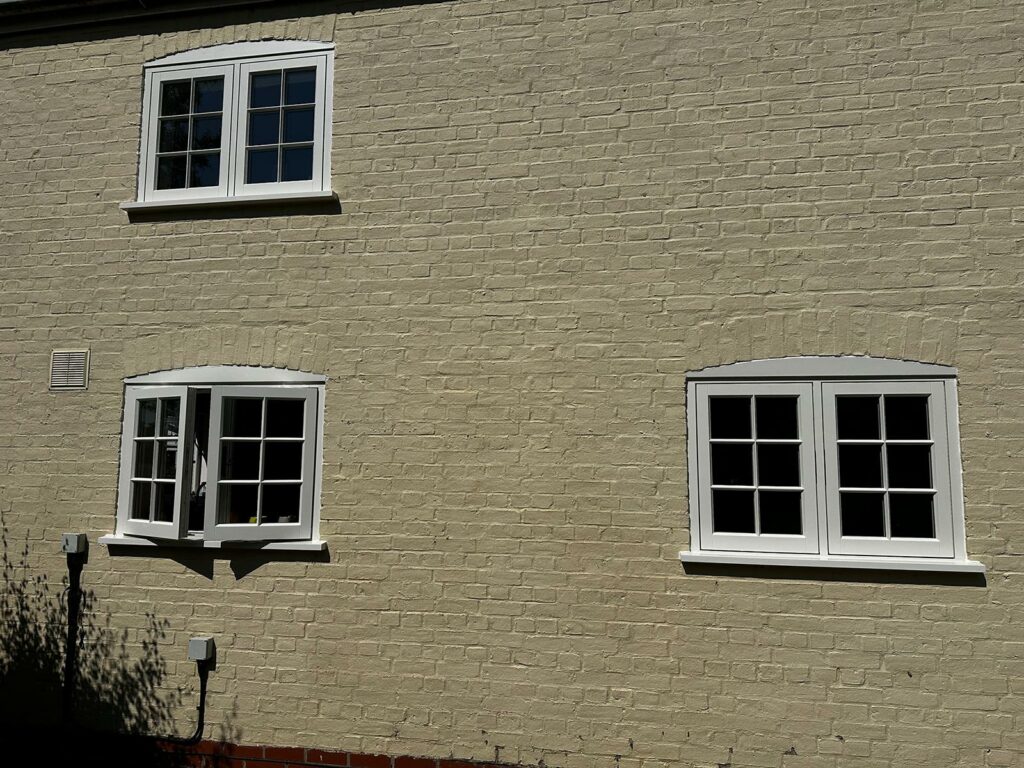 white casement windows on a side of a bricked building