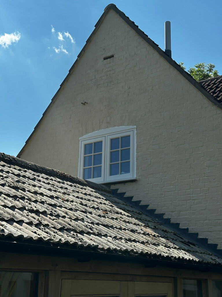 white casement windows on a side of a bricked building