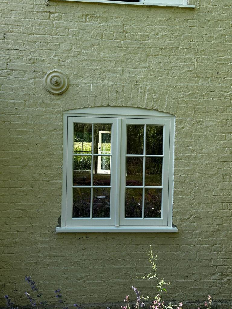 white casement windows on a side of a bricked building