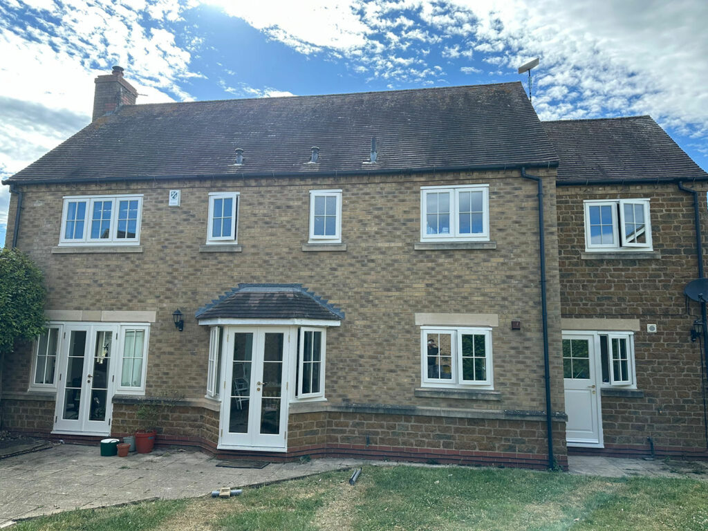 the rear of a home with two sets of french doors and white windows