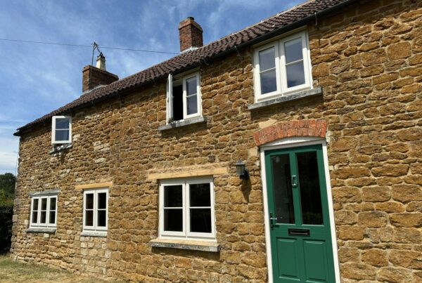 white windows and a green front door on a stone cottage