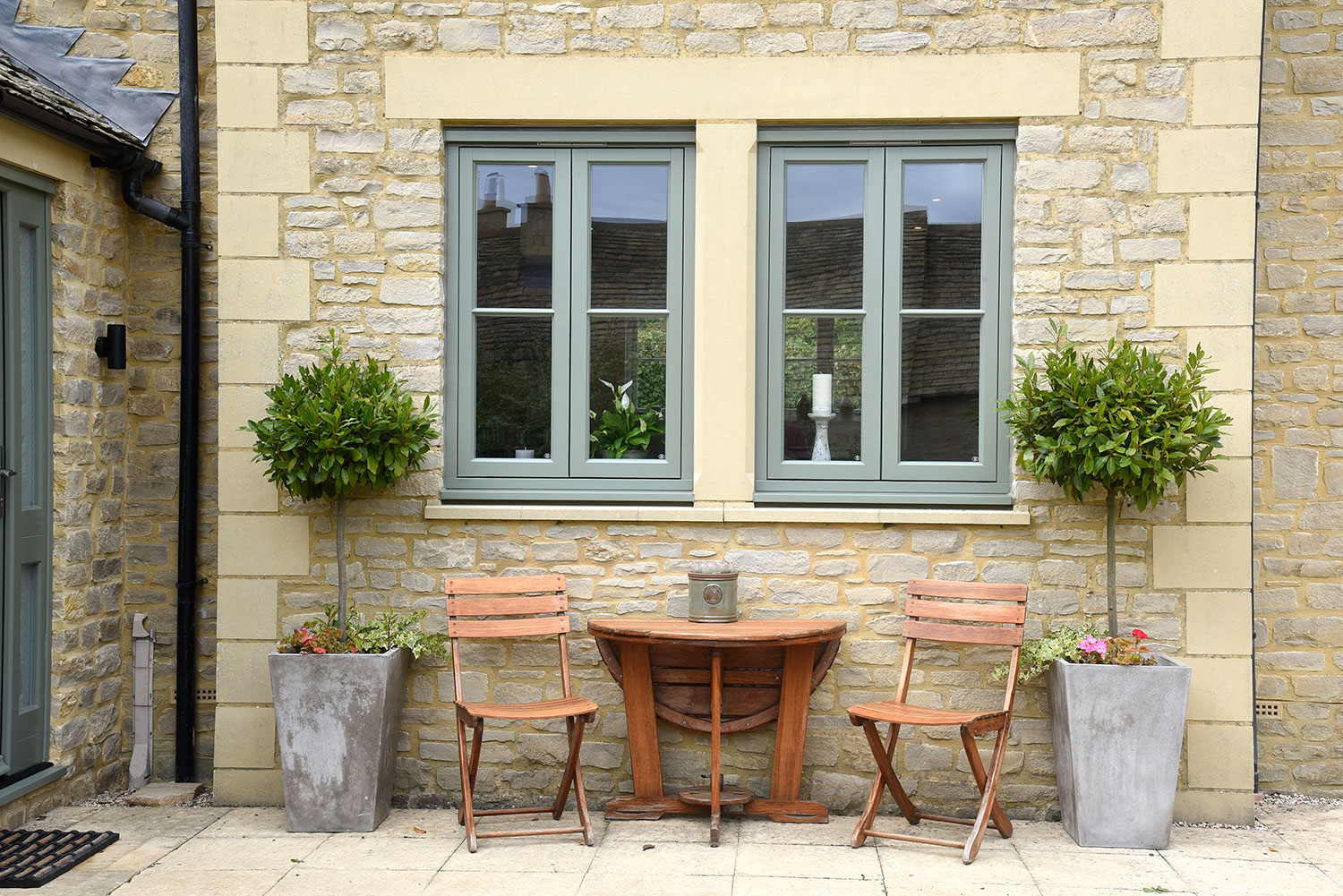 two casement windows behind a wooden table and chairs