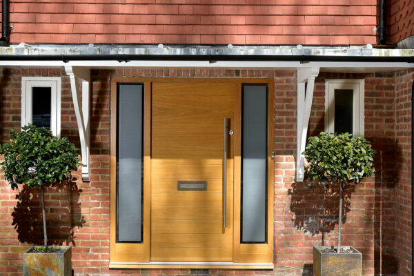 a contemporary oak stained front door with sidelights
