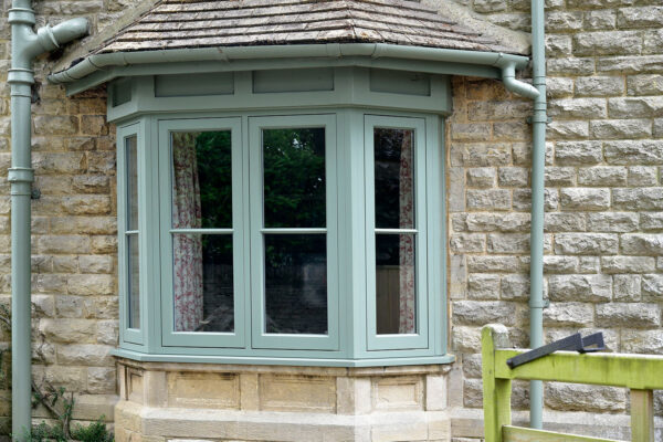 green casement windows on a stone property
