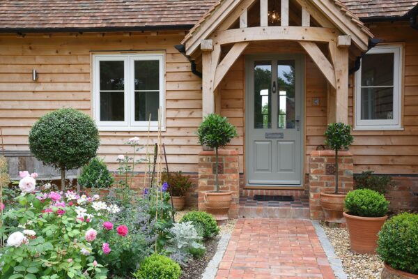 a timber clad building with a french grey front door and white casement windows