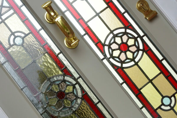 a stained glass door with a polished brass doctors knocker