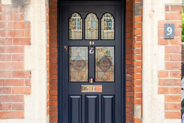 a dark blue front door with bespoke stained glass