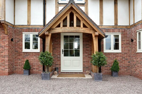 a country home with an elaborate timber canopy and a white front door