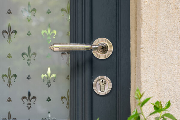 a silver door handle and patterned glass in a fleur de lys style