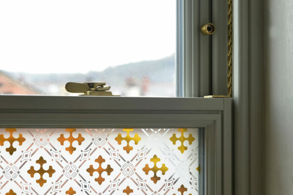 a sash window with brass hardware and gothic etched glass