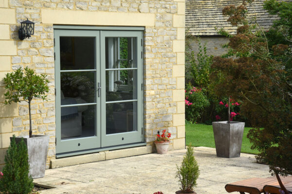a set of green french doors on a cotswolds stone property