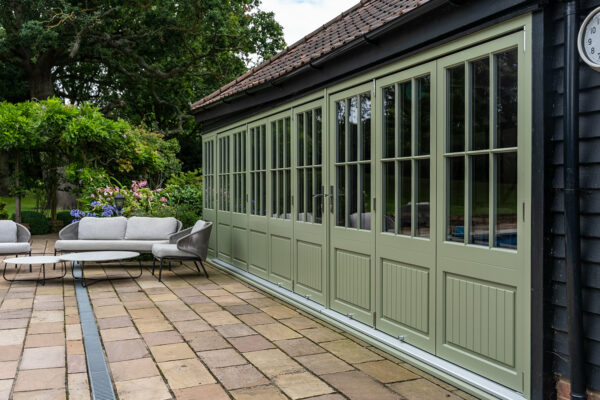 two sets of green bifold doors on a poolhouse