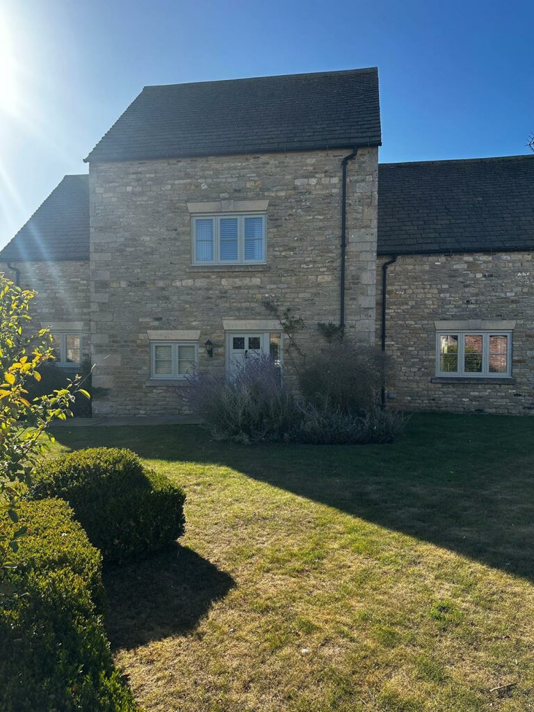 the front of a large stone faced property with new windows and doors