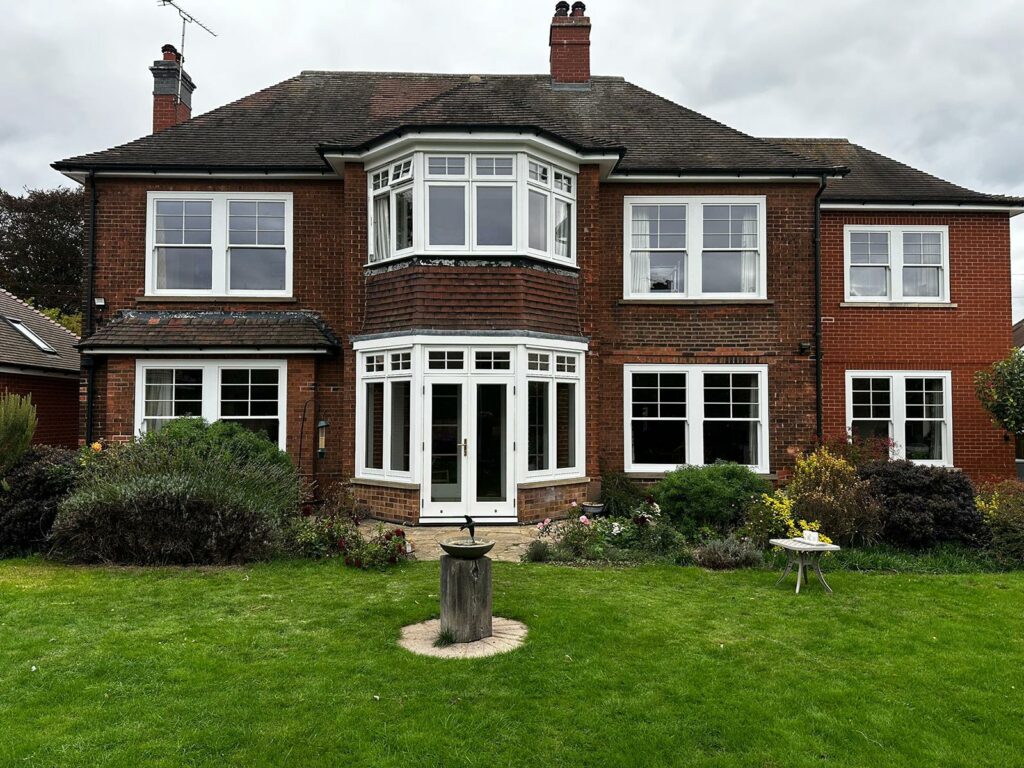a large red brick home with sash windows and french doors, in front of a generously sized garden