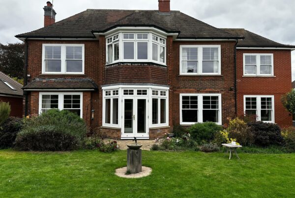 a large red brick home with sash windows and french doors, in front of a generously sized garden