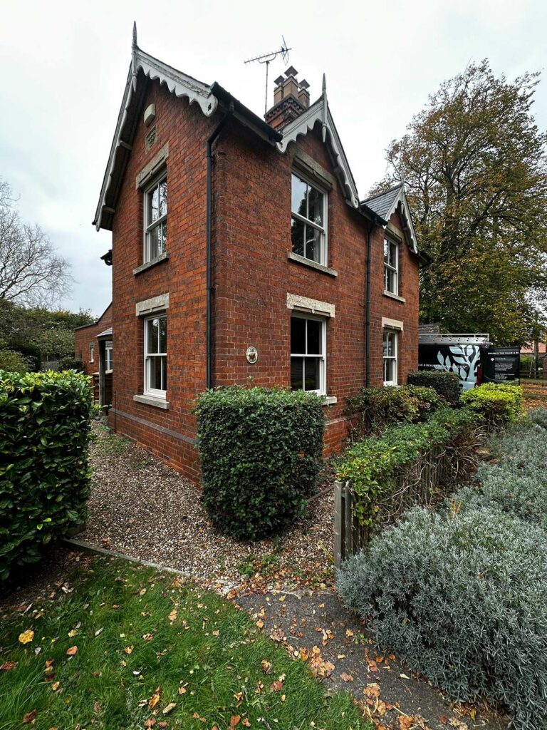 a red brick detached home with white sash windows