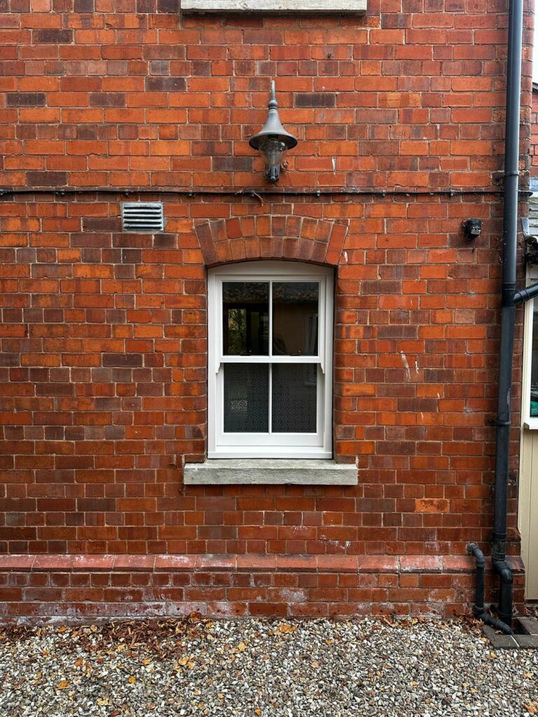 a red brick detached home with white sash windows