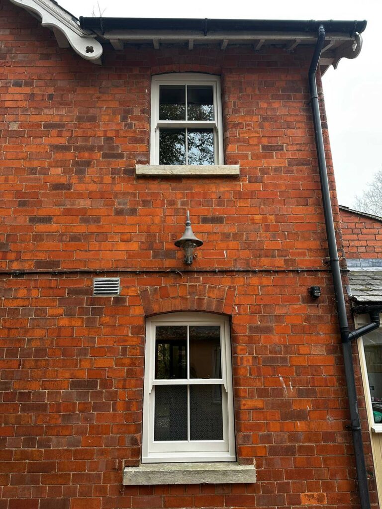 a red brick detached home with white sash windows