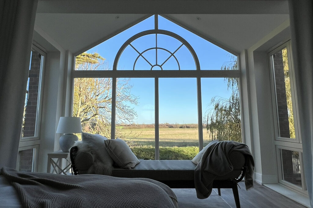a large arched window with glazing bars, behind a sofa