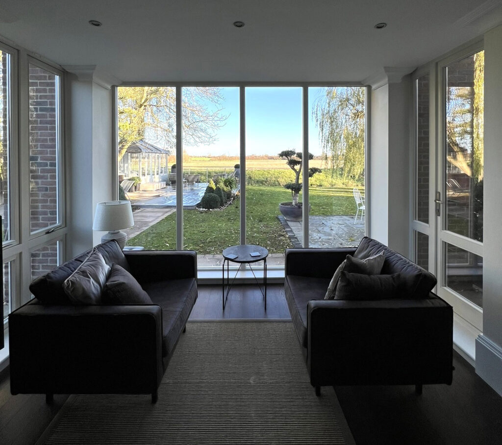 a sitting room with two sofas and large fully glazed windows
