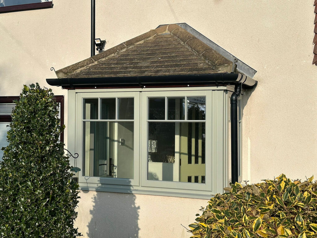 the porch of a house with a victorian style front door and lipped casement windows