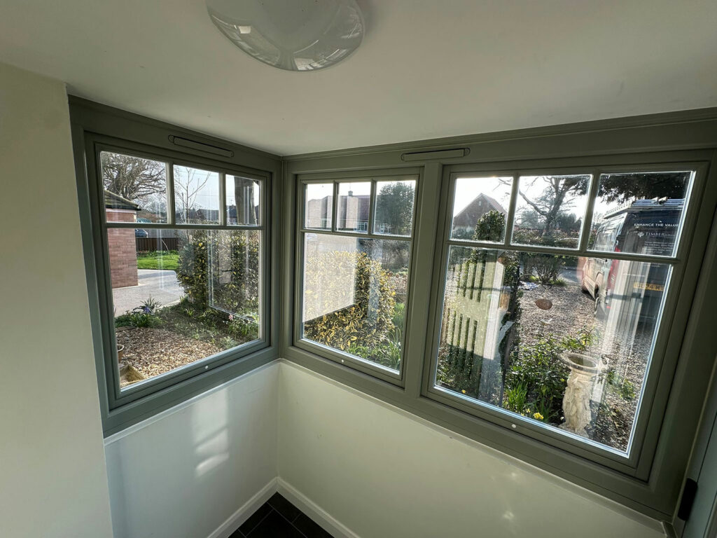 the porch of a house with a victorian style front door and lipped casement windows