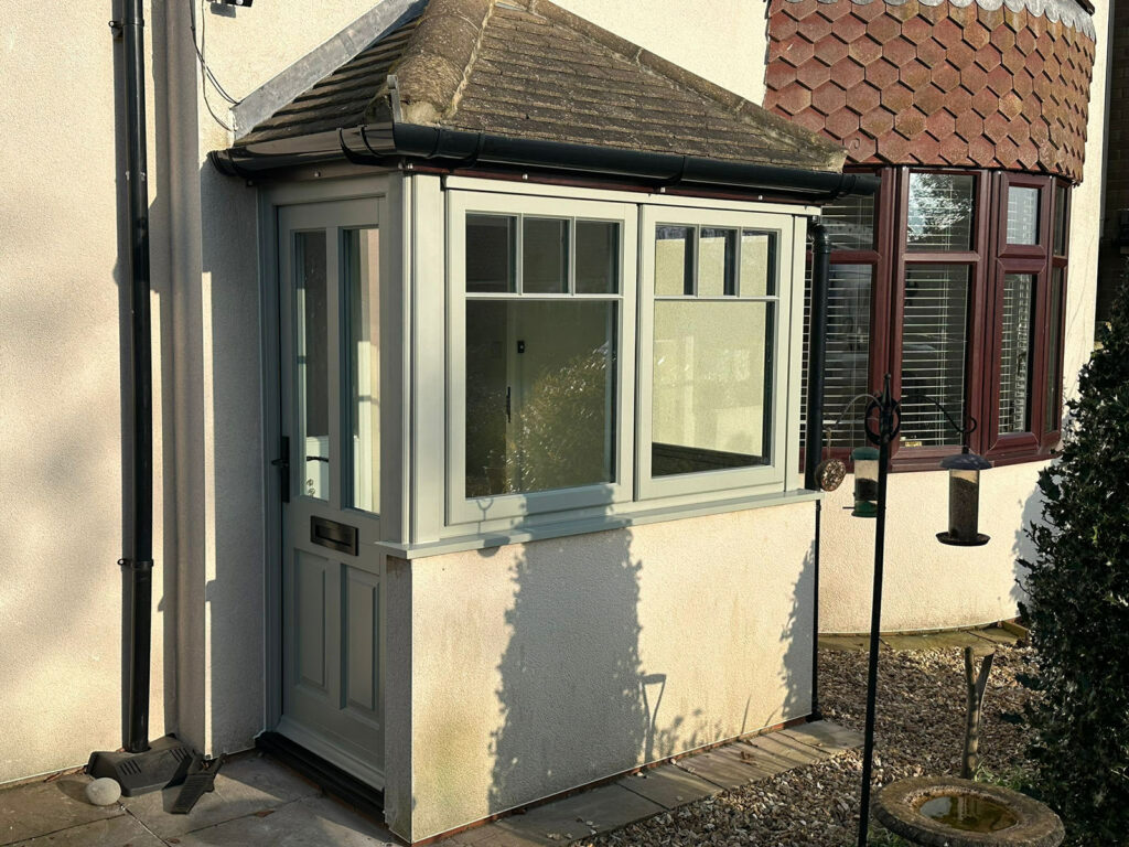 the porch of a house with a victorian style front door and lipped casement windows