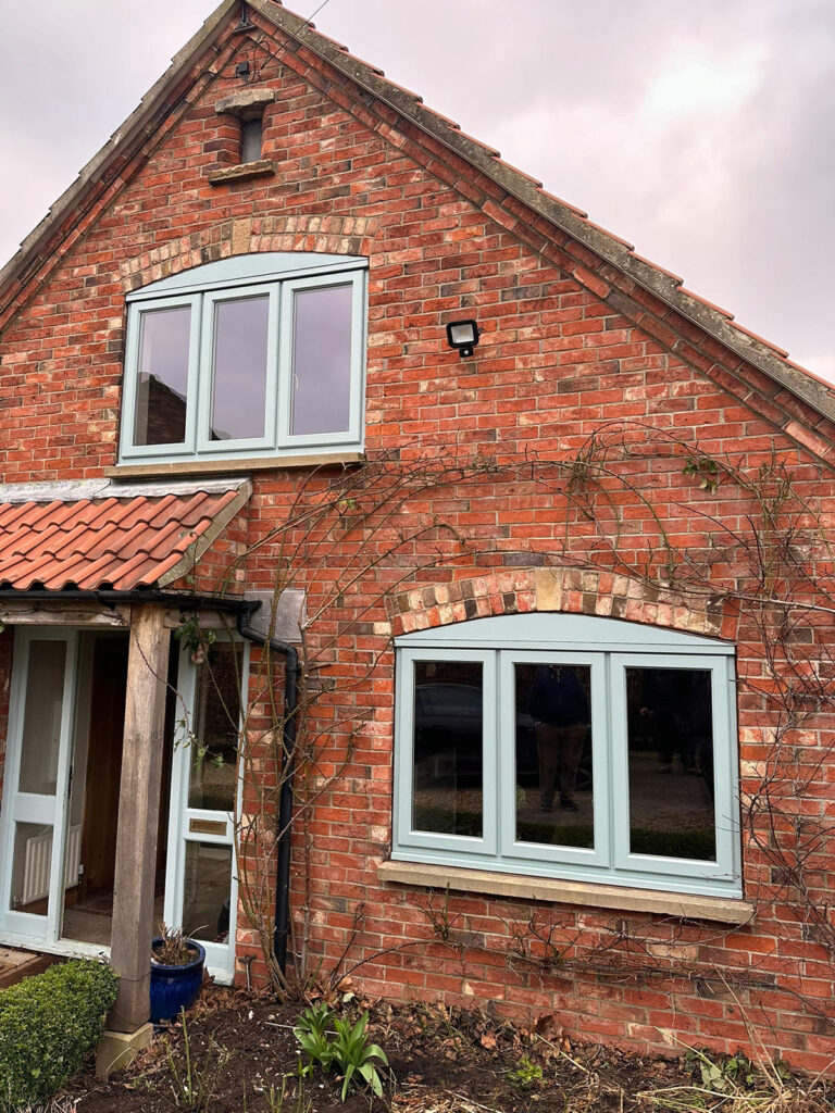 a red brick house with light blue stormproof windows