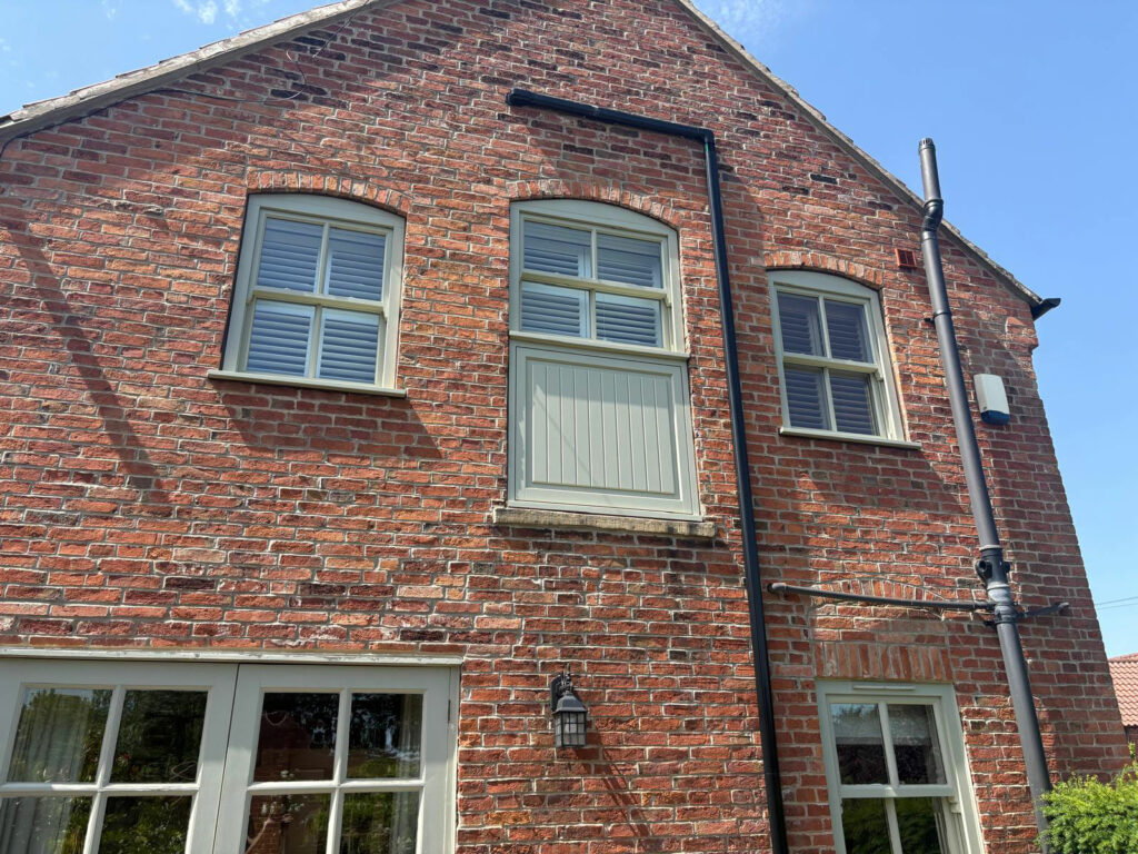 the side of a large red brick home with timber sash windows
