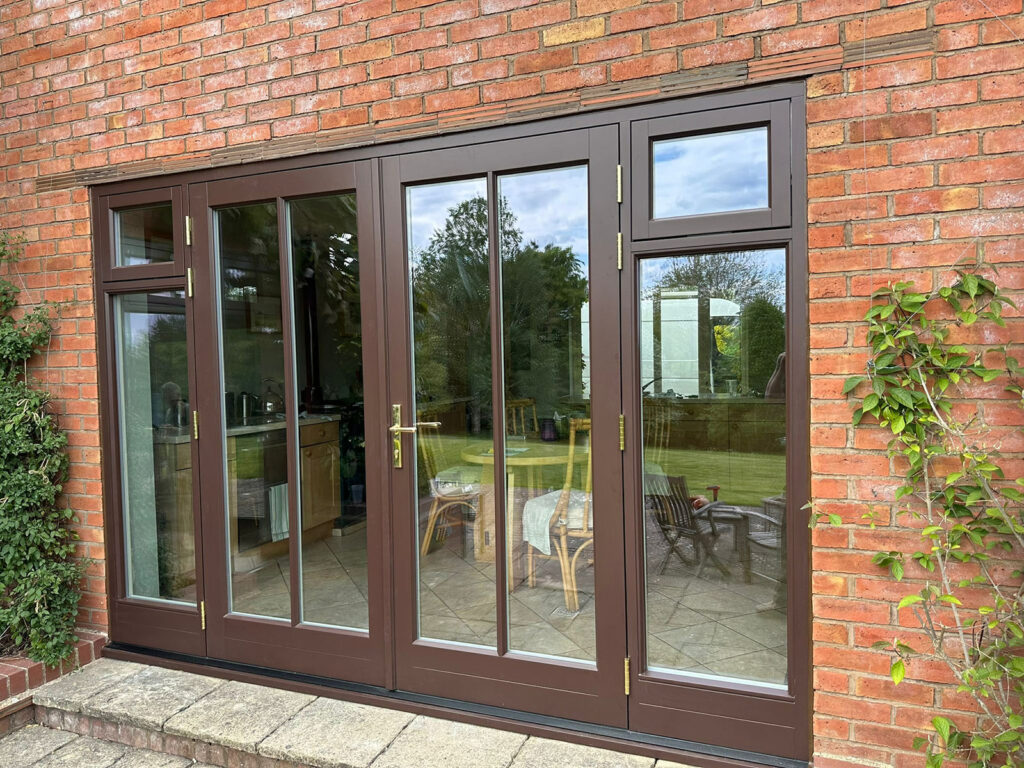 a set of brown french doors with vertical glazing bars and fanlights