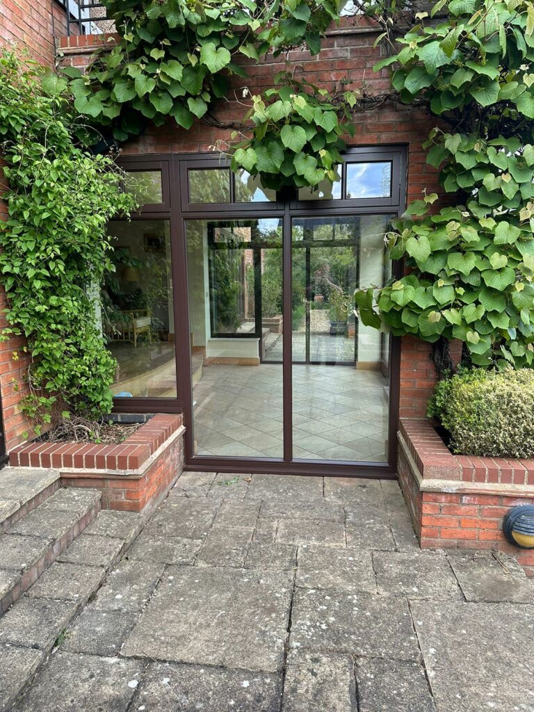 large fully glazed brown frames surrounded by ivy