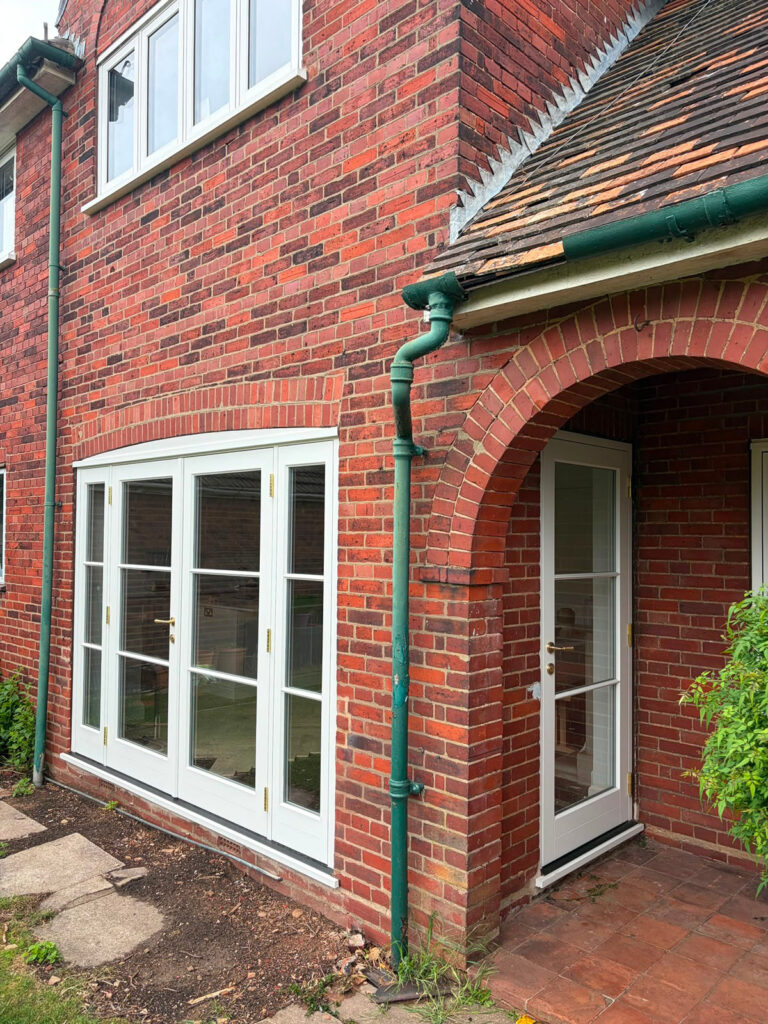 a set of white french doors and singular entrance door on a red brick house