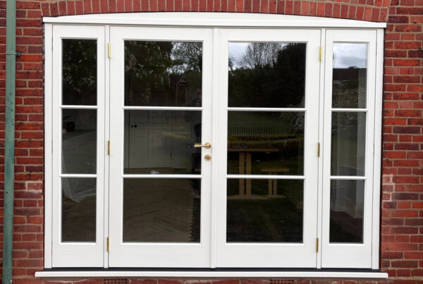A white set of French doors with sidelights on a red brick house.