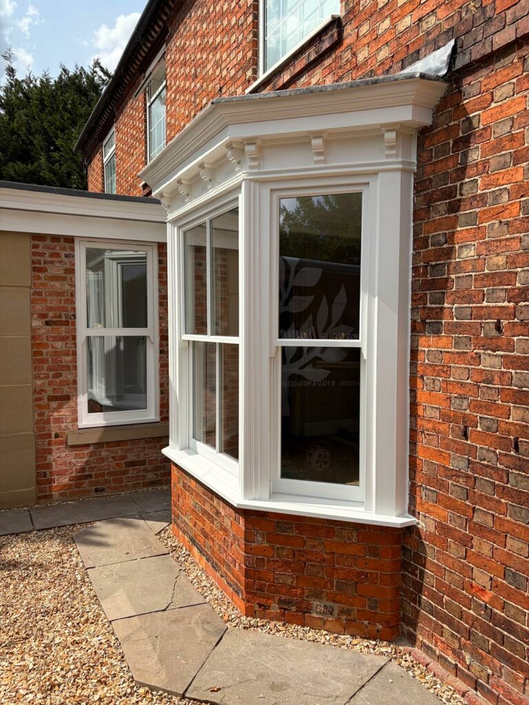 a white victorian sash bay window on a red brick home
