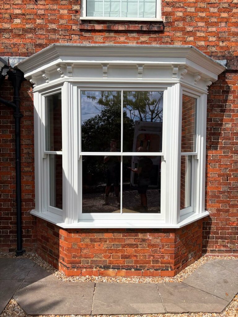 a white victorian sash bay window on a red brick home