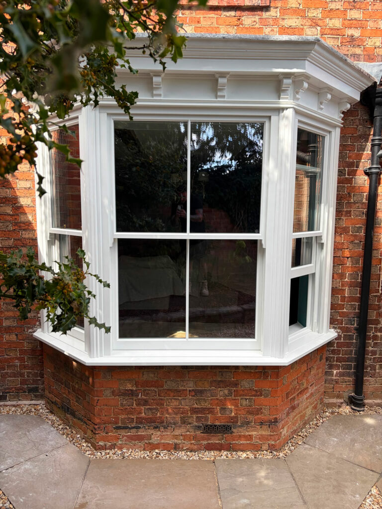 a white victorian sash bay window on a red brick home