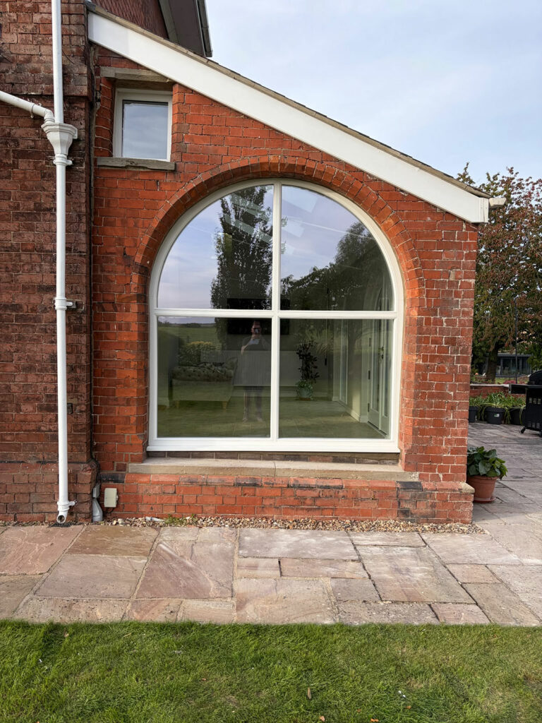 a very large, arched fixed white window frame